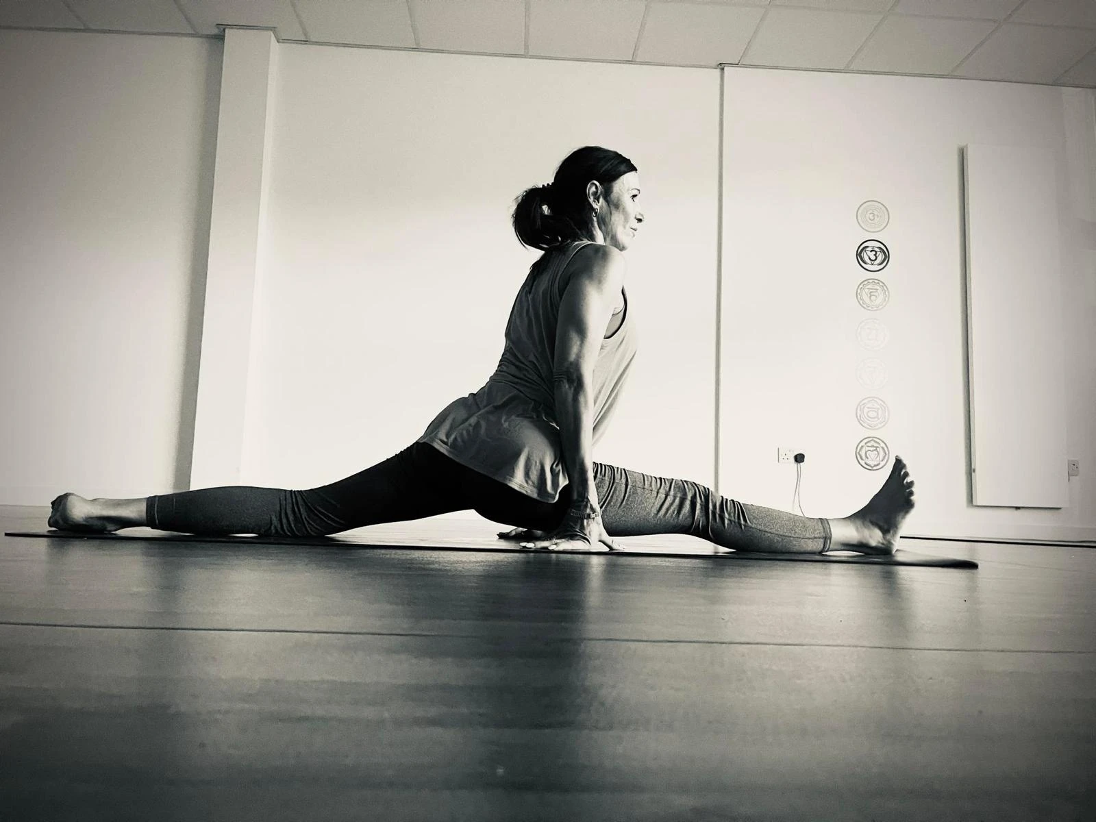 Anna in a deep stretch on her mat in a bright, calm studio